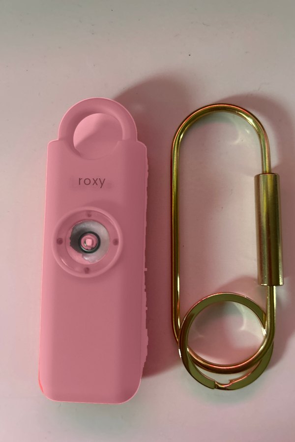 Alarme personnelle Roxy rose posee a plat avec son mousqueton dore