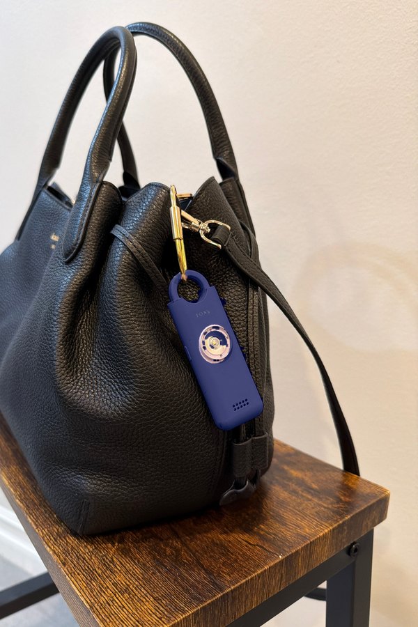 Alarme Roxy bleu marine suspendue a la anse d'un sac a main noir